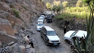 مركبات وشاحنات محملة بالبضائع تعبر بحذر  طريق جبلية وعرة وغير معبدة في جنوب غرب اليمن المحاصرة