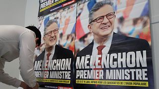 A supporter of far-left leader Jean-Luc Melenchon sticks electoral posters reading "Melenchon Prime Minister" before a local meeting, Thursday, May 5, 2022 in Lille.