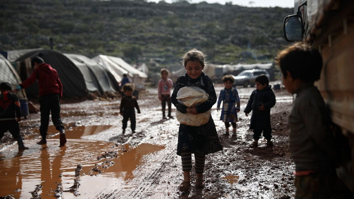 لاجئون سوريون يمشون في مخيم للنازحين غطت طريقه الأوحال بالقرب من قرية كفر عروق في محافظة إدلب - سوريا. 2021/06/28
