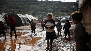 لاجئون سوريون يمشون في مخيم للنازحين غطت طريقه الأوحال بالقرب من قرية كفر عروق في محافظة إدلب - سوريا. 2021/06/28