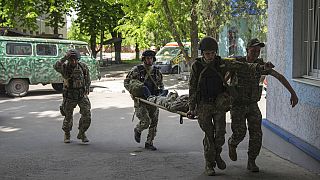 Украинские военные несут однополчанина в госпиталь в Донецкой области 9 мая 2022