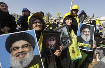  أنصار حزب الله اللبناني يرفعون صور حسن نصر الله وهم يحتشدون لحضور خطابه، الذي تم بثه على شاشة عملاقة، في مدينة النبطية الجنوبية، 9 مايو 2022.