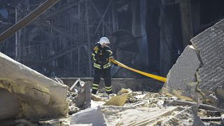 Украинский пожарный работает около разрушенного ракетой здания 10 мая 2022