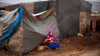 A Syrian young woman holds a baby in a refugee camp for displaced people supported by the Turkish Red Crescent in Sarmada district, north of Idlib city, Syria.