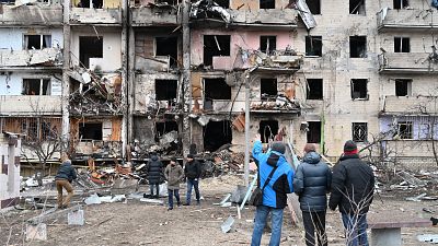 Buildings in Kyiv's suburbs were hit by military fire on February 24, hours after a cyber attack disrupted internet connections in Ukraine