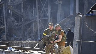 Soldados ucranianos nos escombros de um edifício após um bombardeamento da Rússia