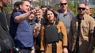 German Foreign Minister Annalena Baerbock, center, and a Ukrainian War Prosecutor talk as they stand near a mass grave in Bucha, on the outskirts of Kyiv, 10 May 2022.