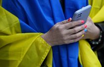 A woman wears a Ukrainian flag over her shoulders during a gathering outside Russia's embassy in Lisbon.