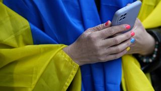 A woman wears a Ukrainian flag over her shoulders during a gathering outside Russia's embassy in Lisbon.