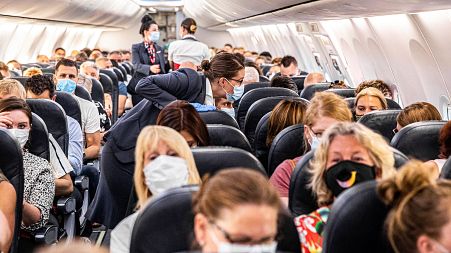 Passengers departing from Amsterdam's Schiphol airport, wearing masks.