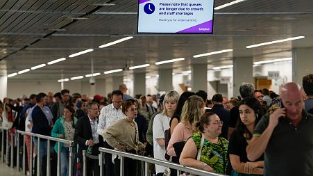 Travellers wait in long lines to check in and board flights at Amsterdam's Schiphol Airport.