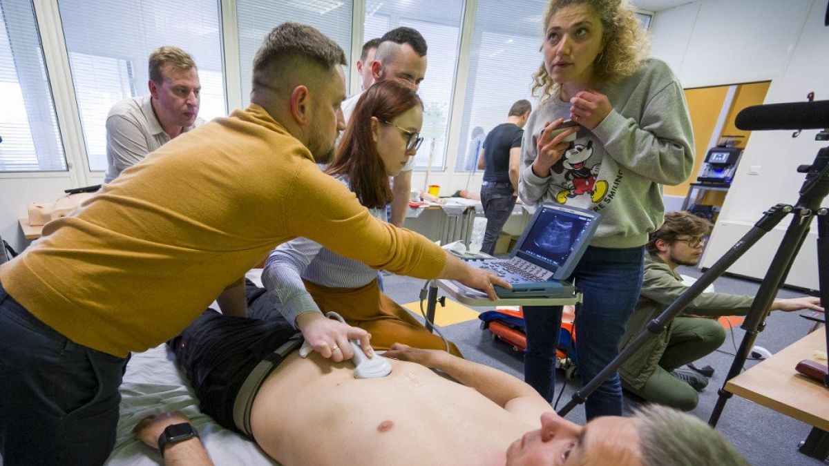 Des soignants ukrainiens apprennent à utiliser un échographe sur leur collègue.