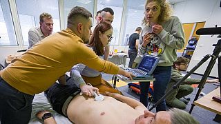 Des soignants ukrainiens apprennent à utiliser un échographe sur leur collègue.