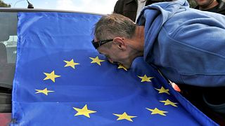 A man kisses the EU flag attached on the windshield of a car, celebrating the recommendation of European Commission to open accession talks with Macedonia, Wednesday, Oct. 14