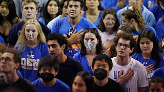 Estudiantes universitarios escuchan el himno nacional durante un partido de voleibol en Los Ángeles, EEUU