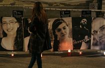 A woman watches photos of the victims of the “Colectiv” nightclub fire during a vigil in memory of them on October 30, 2021 in Bucharest, Romania