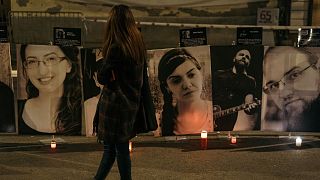 A woman watches photos of the victims of the “Colectiv” nightclub fire during a vigil in memory of them on October 30, 2021 in Bucharest, Romania
