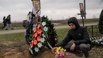 Yura Nechyporenko, 15, places a chocolate at the grave of his father Ruslan Nechyporenko at the cemetery in Bucha, on the outskirts of Kyiv, Ukraine, on April 21, 2022.