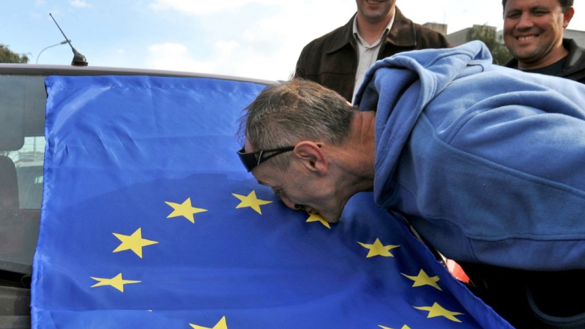 Un hombre besa la bandera de la UE, celebrando la recomendación de la Comisión Europea de iniciar conversaciones de adhesión con Macedonia