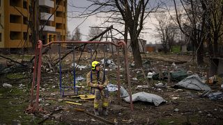 Un bombero se sienta en un columpio junto a un edificio destruido por una bomba rusa en Chernihiv, Ucrania, el viernes 22 de abril de 2022