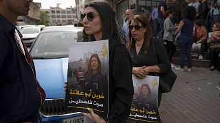 فلسطينيون يحملون لافتات وصور لشيرين أبو عاقلة تقول "شيرين صوت فلسطين"، أمام مكتب قناة الجزيرة في مدينة رام الله بالضفة الغربية.