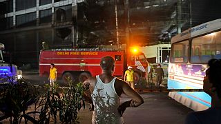 A person watches as fire officials douse a fire in a four storied building, in New Delhi, India, Saturday, May 14, 2022.