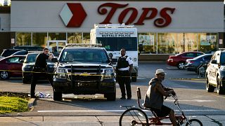 Un ciclista se detiene al pasar por la escena de un tiroteo en un supermercado, en Buffalo, Nueva York, el domingo 15 de mayo de 2022.