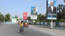 صومالي يقود دراجته الهوائية بجانب لافتات انتخابية لمرشحين للرئاسة في شارع بمقديشو، الصومال.