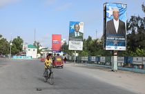 صومالي يقود دراجته الهوائية بجانب لافتات انتخابية لمرشحين للرئاسة في شارع بمقديشو، الصومال.