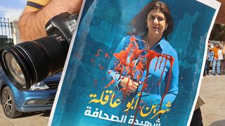 صحفي يرفع ملصقا لشرين أبو عاقلة تنديدا لاغتيالها في مسيرة في مدينة بيت لحم، الضفة الغربية. 