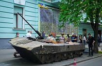 People look at a Russian military vehicle destroyed by the Ukrainian troops and taken to the capital Kyiv as a reminder of war, May 12, 2022.