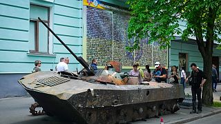 People look at a Russian military vehicle destroyed by the Ukrainian troops and taken to the capital Kyiv as a reminder of war, May 12, 2022. 