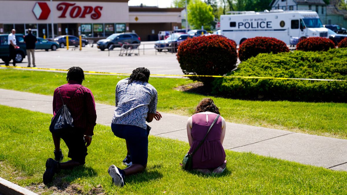 La gente reza fuera de la escena del tiroteo del sábado en un supermercado, en Buffalo, Nueva York, el domingo 15 de mayo de 2022.