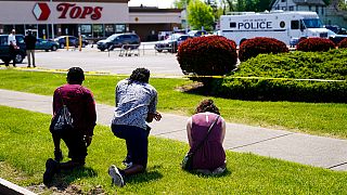 La gente reza fuera de la escena del tiroteo del sábado en un supermercado, en Buffalo, Nueva York, el domingo 15 de mayo de 2022.