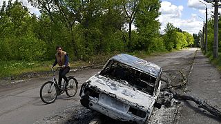 Radfahrer und zerstörtes Auto im Osten der Ukraine