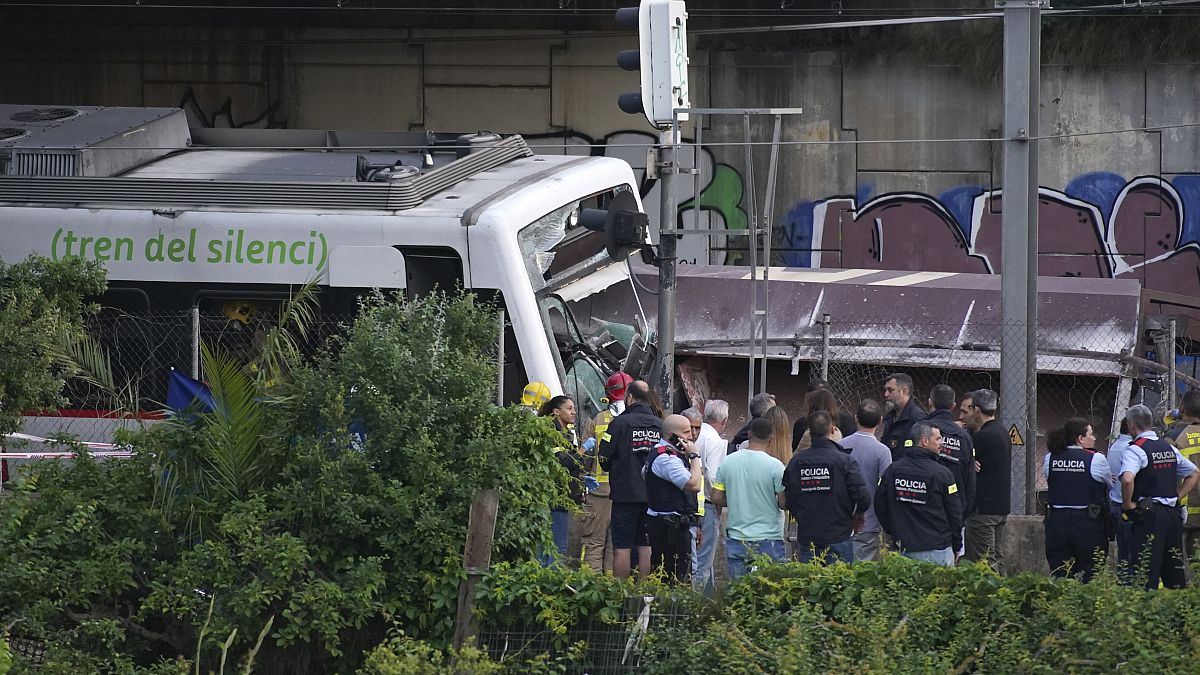 Police and rescue workers stand by the wreckage after the train crash in Sant Boi.