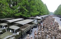 یکی از عکس‌های خبرگزاری مرکزی کره شمالیِ سربازانی را نشان می‌دهد که در کنار صف طولانی کامیون‌های سبز رنگ ایستاده اند.