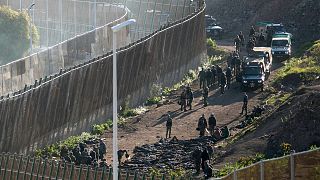 قوات الأمن على الجانب المغربي من الحدود أمام السياج الفاصل بين جيب مليلية الإسباني والمغرب، في مليلية، إسبانيا، مارس 2022.