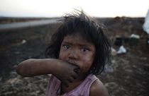Guarani Kaiowa Indian girl cries in front of her hut destroyed by a fire set by an unknown arsonist in their makeshift camp close to their ancestral land.