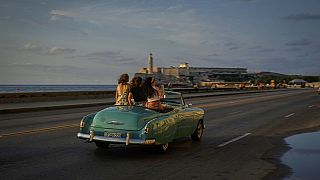 Turistas passeiam num carro antigo no Malecón, em Havana
