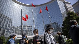 People wearing face masks stand in line for coronavirus tests at an office building in the Dongcheng district of Beijing, Tuesday, April 26, 2022.