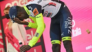 Le cycliste Biniam Girmay après avoir reçu un bouchon de prosecco dans l’œil, alors qu'il célébrait sa victoire sur la 10ème étape du tour d'Italie à Jesii, le 18 mai