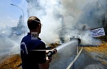 A firefighter sprays water on the burning bails outside the entrance gates of Cyprus' presidential palace in the capital Nicosia, Cyprus, on Wednesday, May 18, 2022.