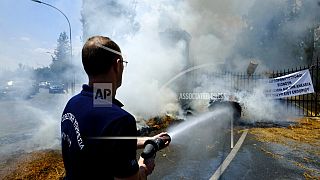 A firefighter sprays water on the burning bails outside the entrance gates of Cyprus' presidential palace in the capital Nicosia, Cyprus, on Wednesday, May 18, 2022. 