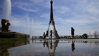 La gente se baña en una fuente a los pies de la Torre Eiffel en París