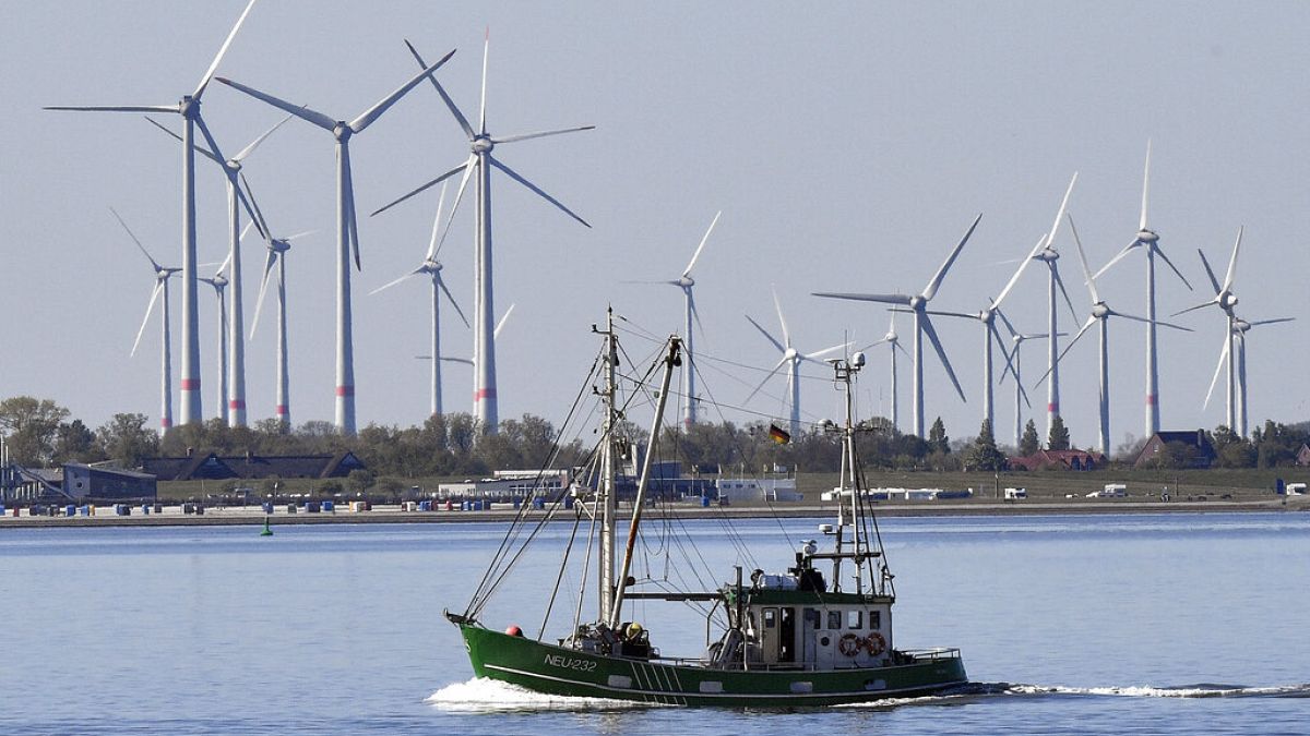  A fisher boat passes wind turbines between the island Langeoog and Bensersiel at the North Sea coast in Germany