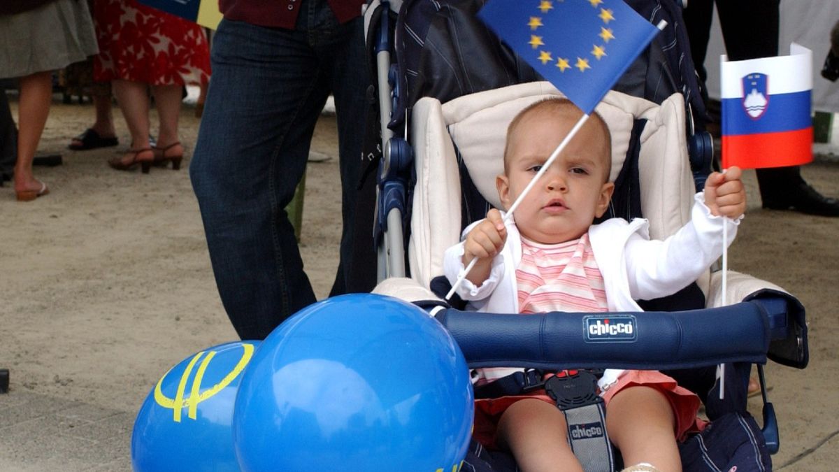 A baby girl waves the European flag along with the Slovenian one while attending a celebration in Brussels, July 11, 2006.