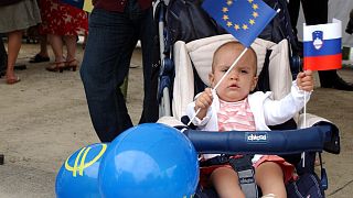 A baby girl waves the European flag along with the Slovenian one while attending a celebration in Brussels, July 11, 2006.