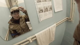 يوليا باييفسكا المعروفة باسم تايرا، تنظر في المرآة وهي تمسك كاميرتها في ماريوبول، أوكرانيا في 03/02/2022