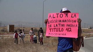 Un migrante sostiene un cartel de protesta contra el Título 42